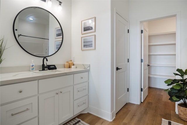 bathroom featuring a closet, baseboards, wood finished floors, and vanity