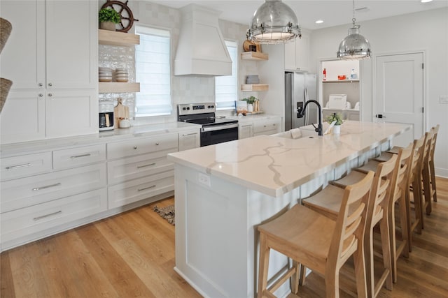 kitchen featuring open shelves, custom exhaust hood, a sink, appliances with stainless steel finishes, and white cabinetry