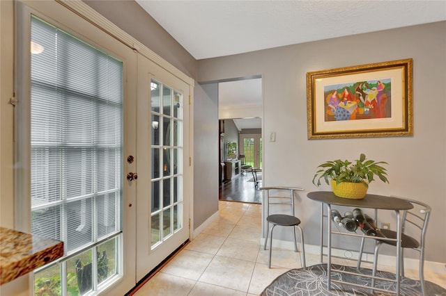 doorway with baseboards and light tile patterned flooring