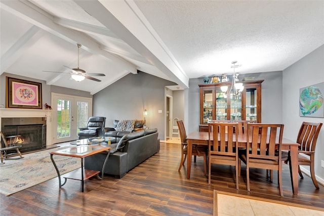 dining room featuring a warm lit fireplace, a textured ceiling, lofted ceiling with beams, and wood finished floors