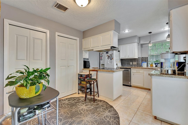 kitchen featuring a peninsula, white cabinets, light tile patterned flooring, and visible vents