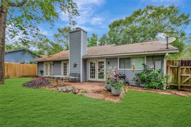 rear view of property with french doors, a yard, fence private yard, a chimney, and a patio area