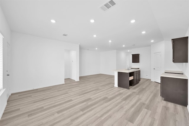 unfurnished living room with light wood finished floors, visible vents, recessed lighting, and a sink