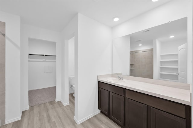 bathroom with visible vents, a walk in closet, toilet, tiled shower, and baseboards