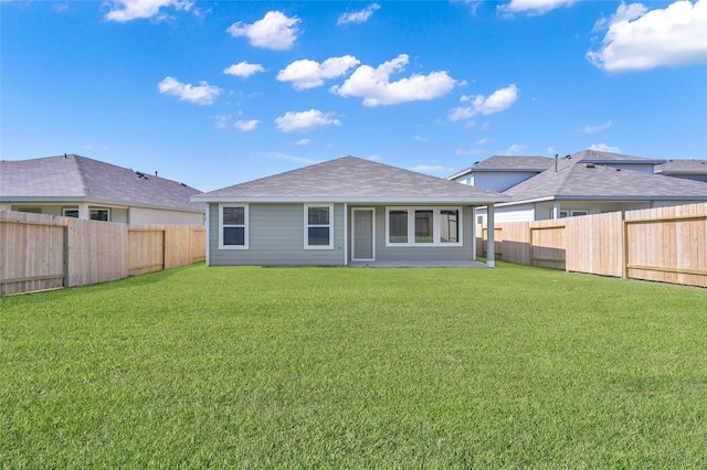 back of house featuring a yard, roof with shingles, and a fenced backyard