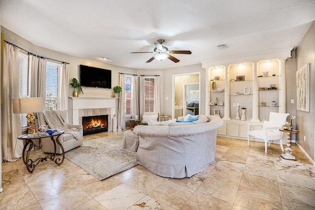 living area with visible vents, plenty of natural light, a tile fireplace, and a ceiling fan