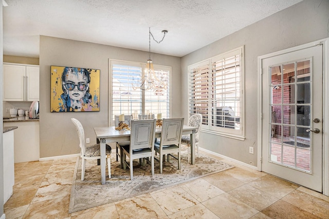 dining space featuring a notable chandelier, baseboards, and a textured ceiling