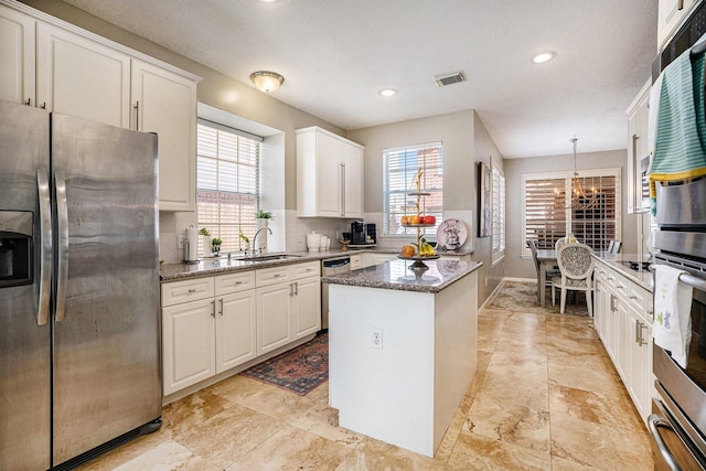 kitchen with visible vents, a sink, backsplash, a center island, and appliances with stainless steel finishes