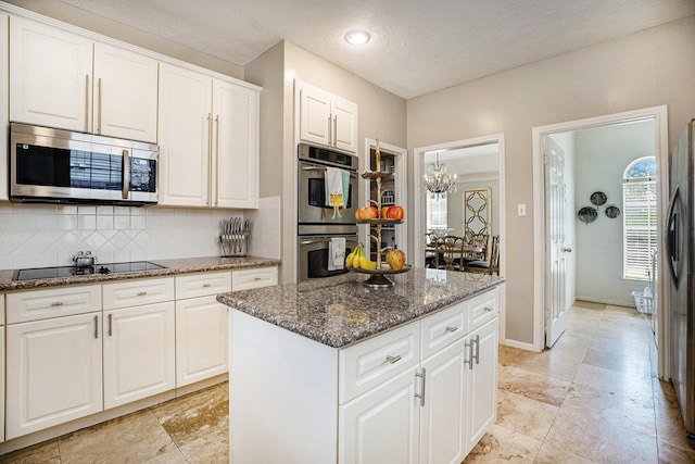 kitchen featuring a center island, dark stone counters, decorative backsplash, appliances with stainless steel finishes, and white cabinets