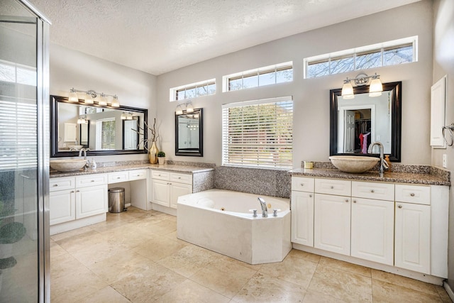 full bathroom featuring vanity, a jetted tub, a stall shower, and a textured ceiling