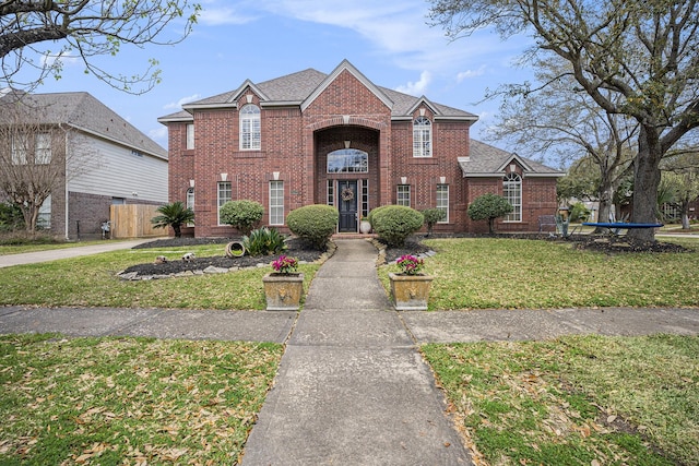 traditional-style home with brick siding, a front yard, and fence