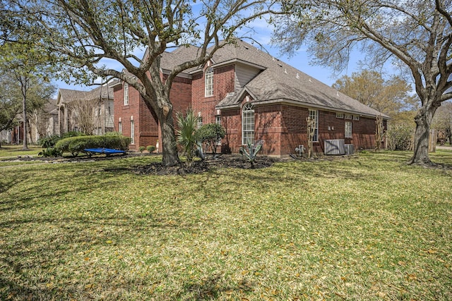 back of property featuring a yard, brick siding, and a shingled roof