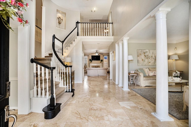 foyer entrance featuring stairs, a high ceiling, baseboards, and ornate columns