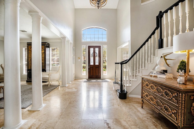 foyer entrance with visible vents, baseboards, stairway, decorative columns, and a high ceiling