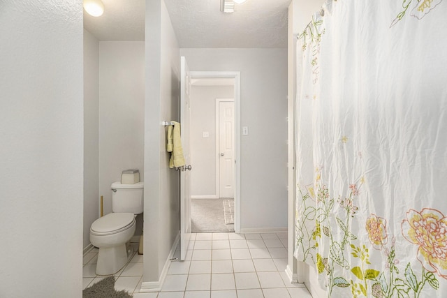 full bath featuring tile patterned flooring, a textured ceiling, toilet, and baseboards