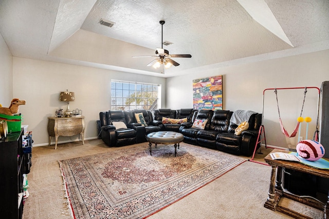 living room with visible vents, a tray ceiling, a textured ceiling, light colored carpet, and ceiling fan