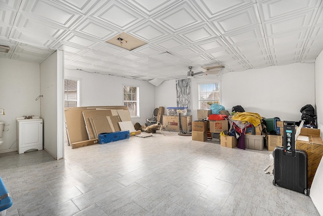 basement featuring a wealth of natural light, an ornate ceiling, a ceiling fan, and a sink