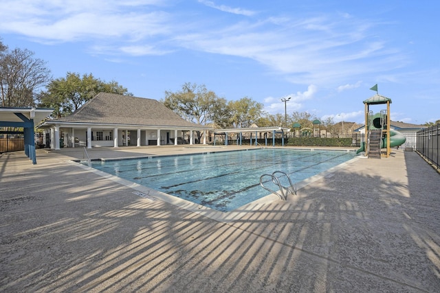 pool with a patio area, fence, and playground community