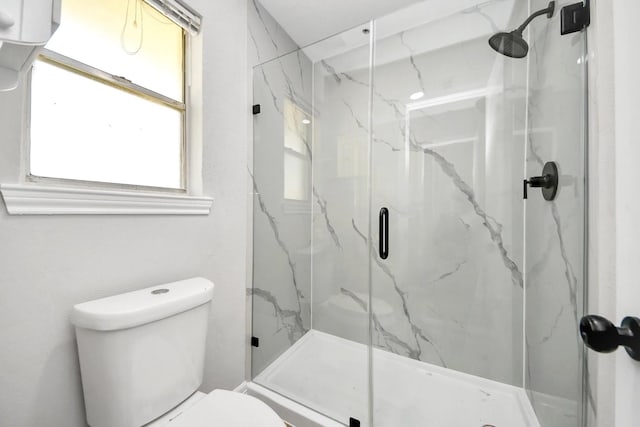 bathroom featuring toilet and a marble finish shower