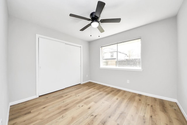 unfurnished bedroom with a closet, a ceiling fan, light wood-type flooring, and baseboards