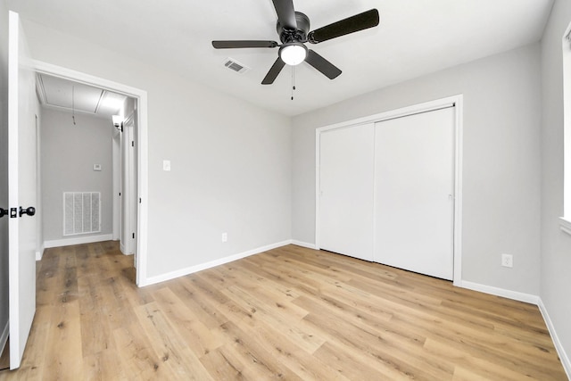 unfurnished bedroom featuring visible vents, light wood-style flooring, attic access, and baseboards