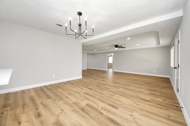 spare room featuring ceiling fan with notable chandelier, light wood-style flooring, baseboards, and visible vents