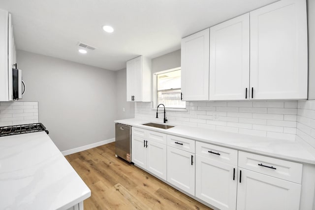 kitchen with visible vents, baseboards, stainless steel appliances, white cabinetry, and a sink