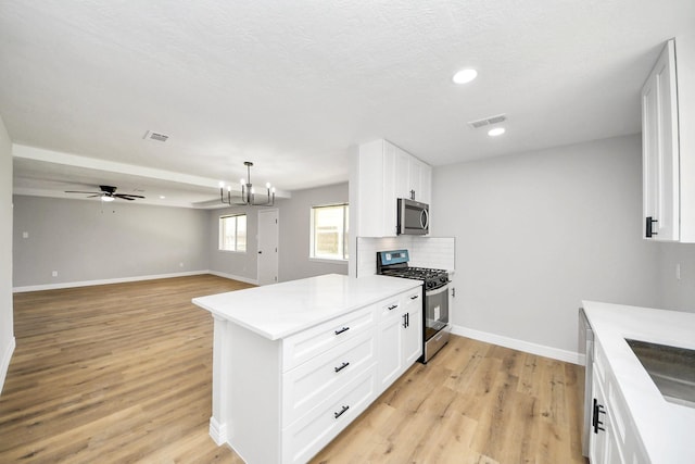 kitchen featuring visible vents, white cabinets, light wood-style floors, appliances with stainless steel finishes, and backsplash