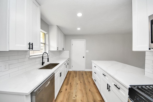 kitchen with white cabinetry, a sink, decorative backsplash, dishwasher, and light wood-type flooring