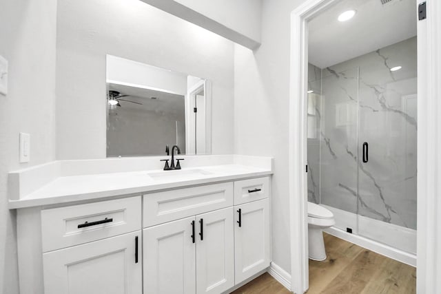 bathroom featuring vanity, wood finished floors, a marble finish shower, ceiling fan, and toilet