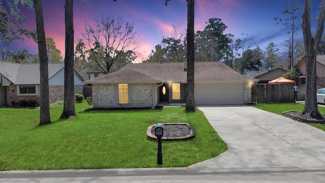 ranch-style home with fence, concrete driveway, a front yard, a garage, and brick siding