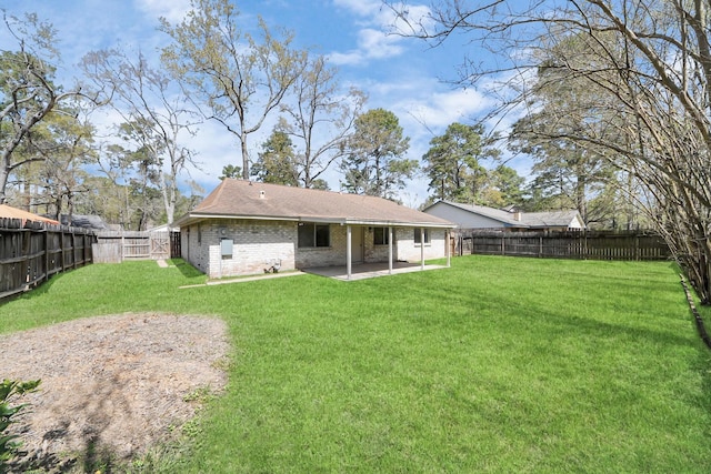 rear view of property with a patio, a yard, a fenced backyard, and brick siding