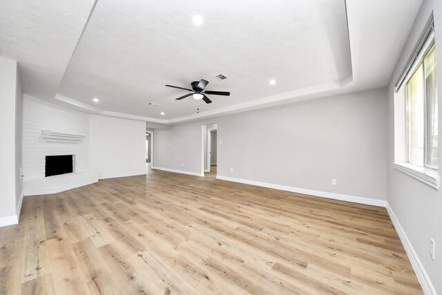 unfurnished living room with light wood-style flooring, baseboards, and a tray ceiling