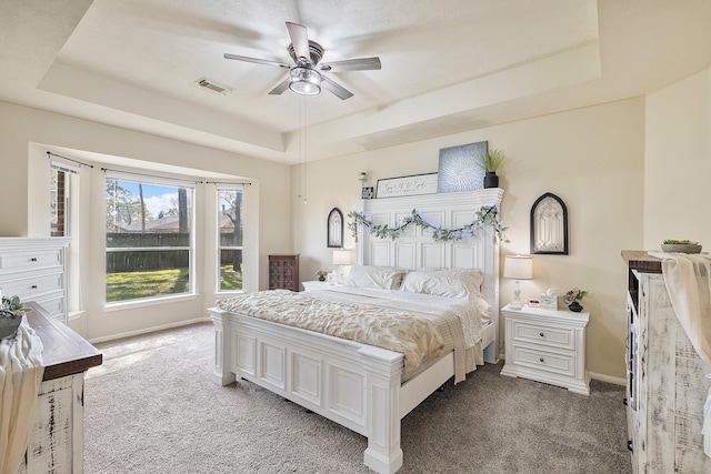 bedroom featuring visible vents, a raised ceiling, light colored carpet, and baseboards