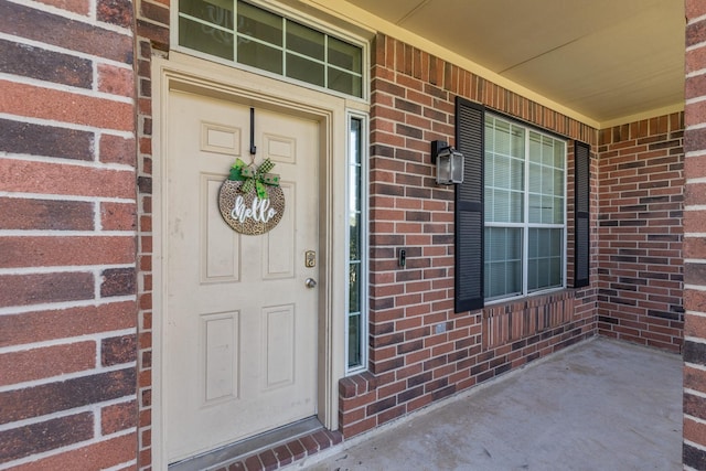 view of exterior entry with brick siding and covered porch