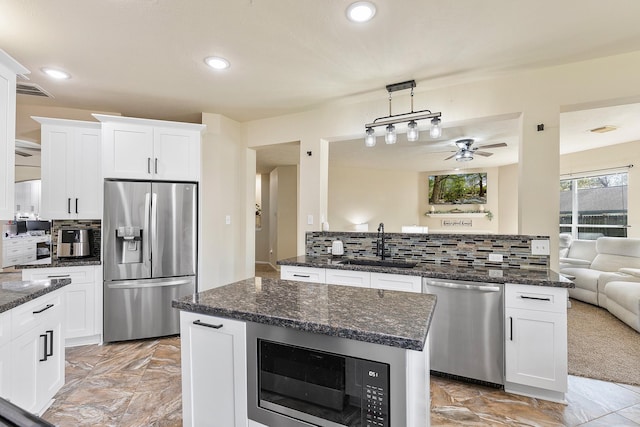 kitchen featuring tasteful backsplash, ceiling fan, a peninsula, stainless steel appliances, and a sink