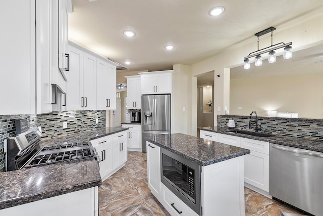 kitchen featuring backsplash, dark stone counters, stainless steel appliances, white cabinetry, and a sink