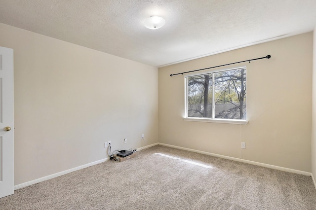 carpeted spare room with baseboards and a textured ceiling