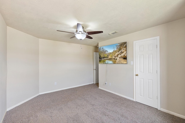 carpeted empty room with visible vents, baseboards, a textured ceiling, and a ceiling fan