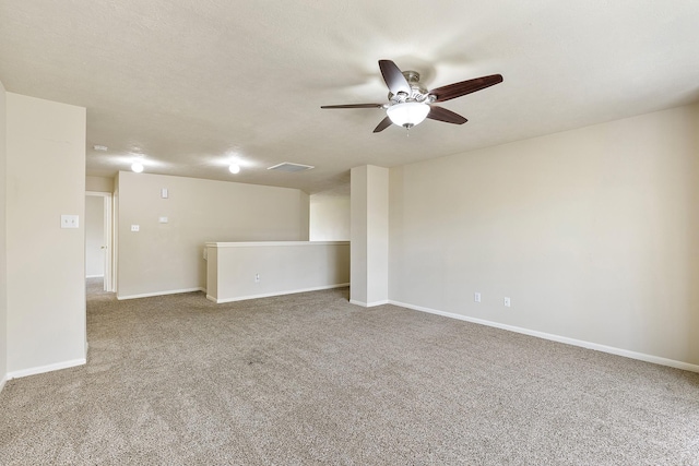 carpeted spare room featuring visible vents, a textured ceiling, baseboards, and a ceiling fan