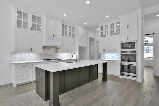 kitchen featuring a sink, light countertops, white cabinets, light wood-style floors, and appliances with stainless steel finishes