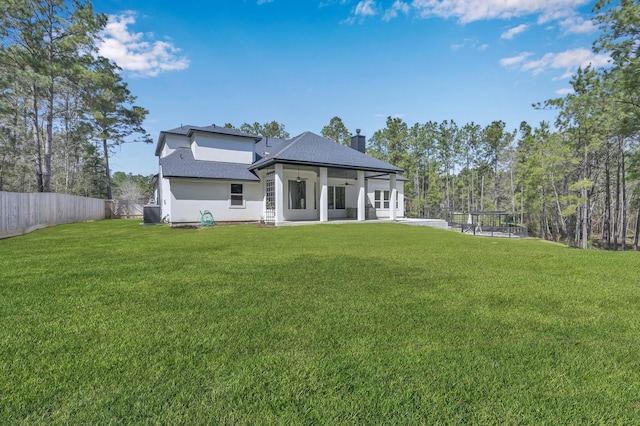 rear view of property with a yard, a shingled roof, a chimney, and fence