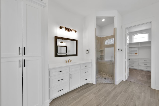 bathroom featuring a closet, a stall shower, vanity, and wood finished floors