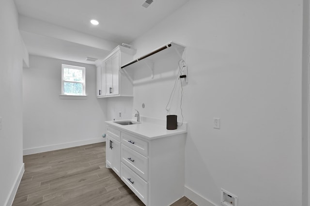 washroom featuring a sink, cabinet space, light wood finished floors, baseboards, and hookup for a washing machine