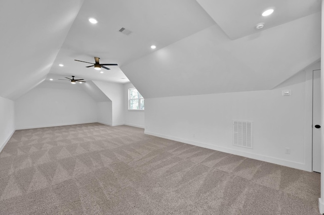 additional living space featuring lofted ceiling, light colored carpet, visible vents, and baseboards