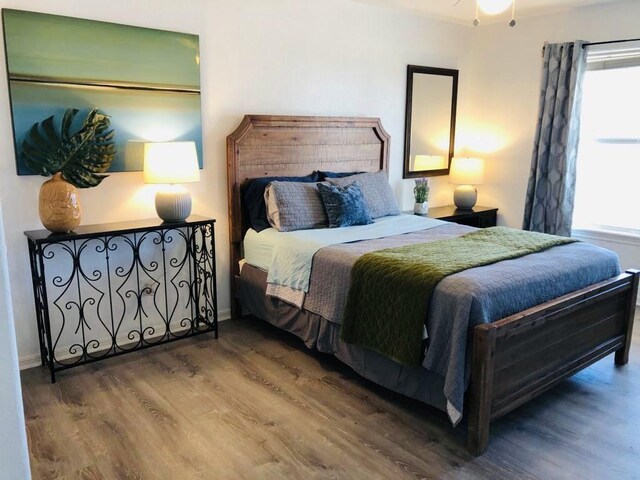 bedroom with multiple windows, baseboards, and wood finished floors