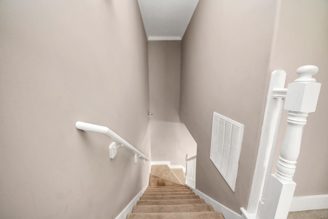 staircase featuring visible vents, baseboards, carpet floors, and ornamental molding