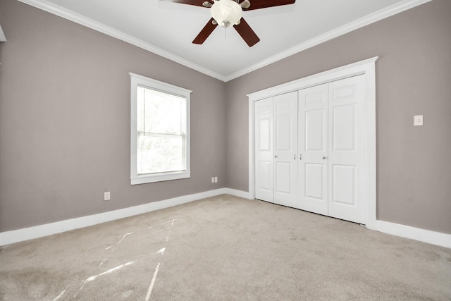 unfurnished bedroom featuring ornamental molding, a closet, carpet floors, baseboards, and ceiling fan