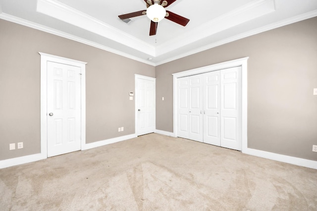 unfurnished bedroom with a tray ceiling, carpet floors, baseboards, and crown molding