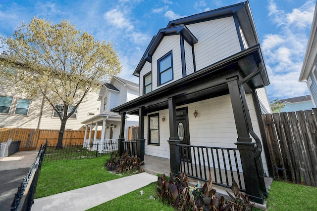 view of front of house with a porch, a front lawn, and fence